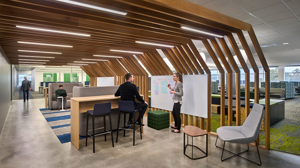 A man and woman standing in a room with chairs and tables.